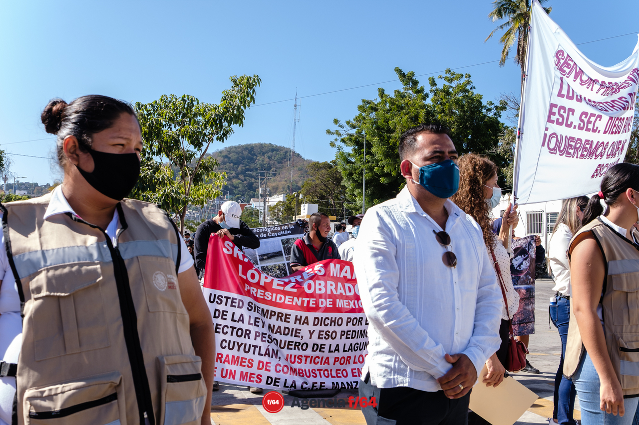 Manifestantes con mantas y peticiones a problemas donde ya anteriormente le han hecho llegar escritos al Presidente. La contaminación del vaso 1 de la laguna de Cuyutlán por la CFE y el intento de instalar una mina de hierro en la comunidad de Canoas en Manzanillo.