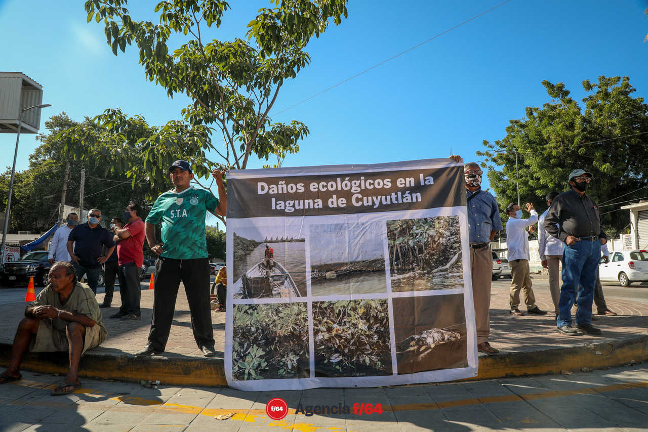 Manifestantes con mantas y peticiones a problemas donde ya anteriormente le han hecho llegar escritos al Presidente. La contaminación del vaso 1 de la laguna de Cuyutlán por la CFE y el intento de instalar una mina de hierro en la comunidad de Canoas en Manzanillo.