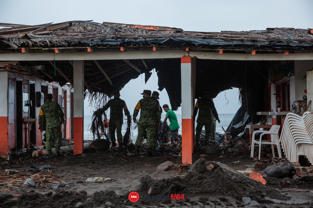 Pobladores y elementos del ejército realizan trabajos de limpieza después de las afectaciones que dejó el huracán Enrique en la comunidad.