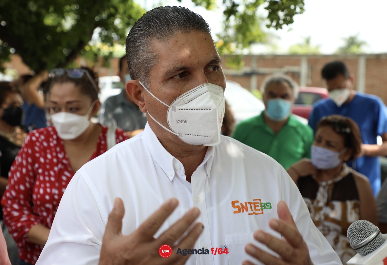 Dirigente del SNTE39, Heriberto Valladares, acompañado de sus colaboradores, camina entre las filas de autos saludando a sus agremiados.