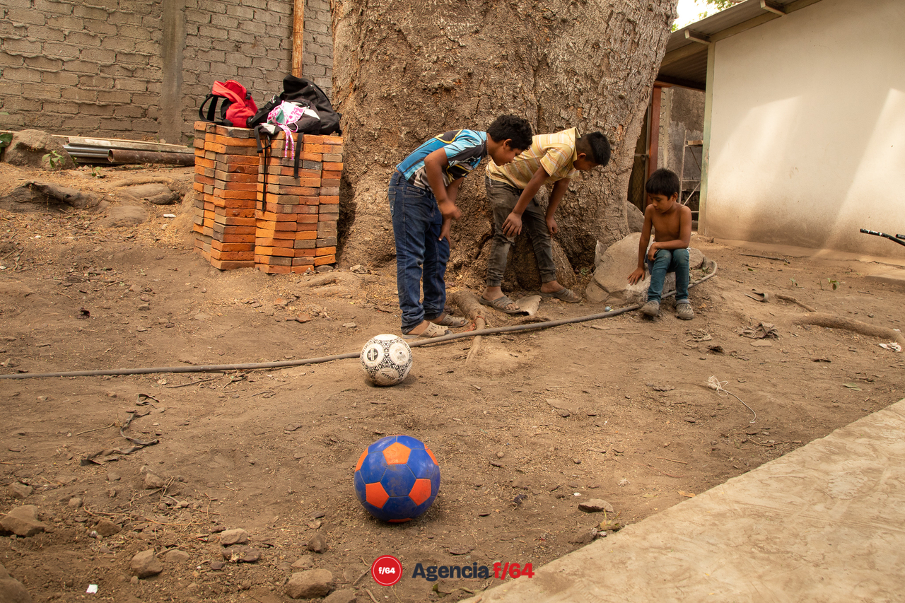 Niños juegan canicas.