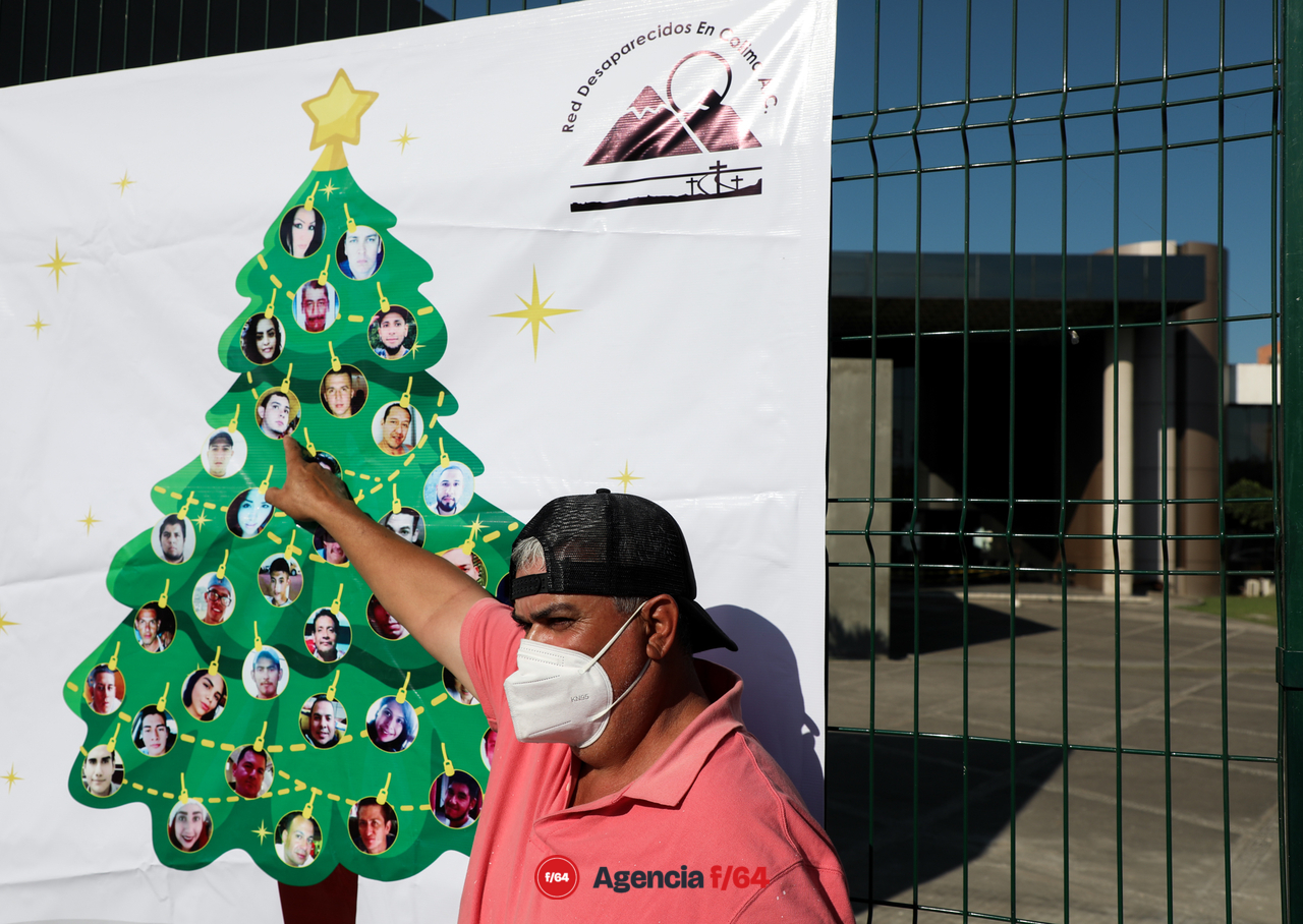 Álvaro Guardado señala la foto de su hijo Álvaro Guardado Silva, desaparecido el 10/03/2018.
Integrantes de la Red Desaparecidos en Colima en la instalación simbólica del Árbol Navideño “decorado” con múltiples esferas las cuales muestran y honran la memoria de sus Familiares Desaparecidos. Ubicación: Edificio de la Fiscalia General del Estado de Colima. 
