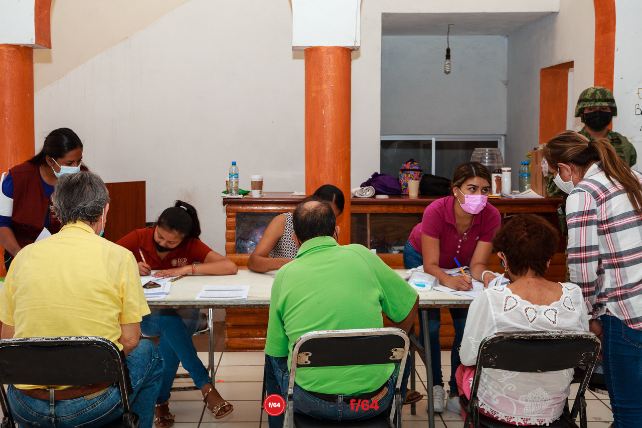 Personal de Gobierno ayudan a los adultos mayores a llenar el formato de registro.