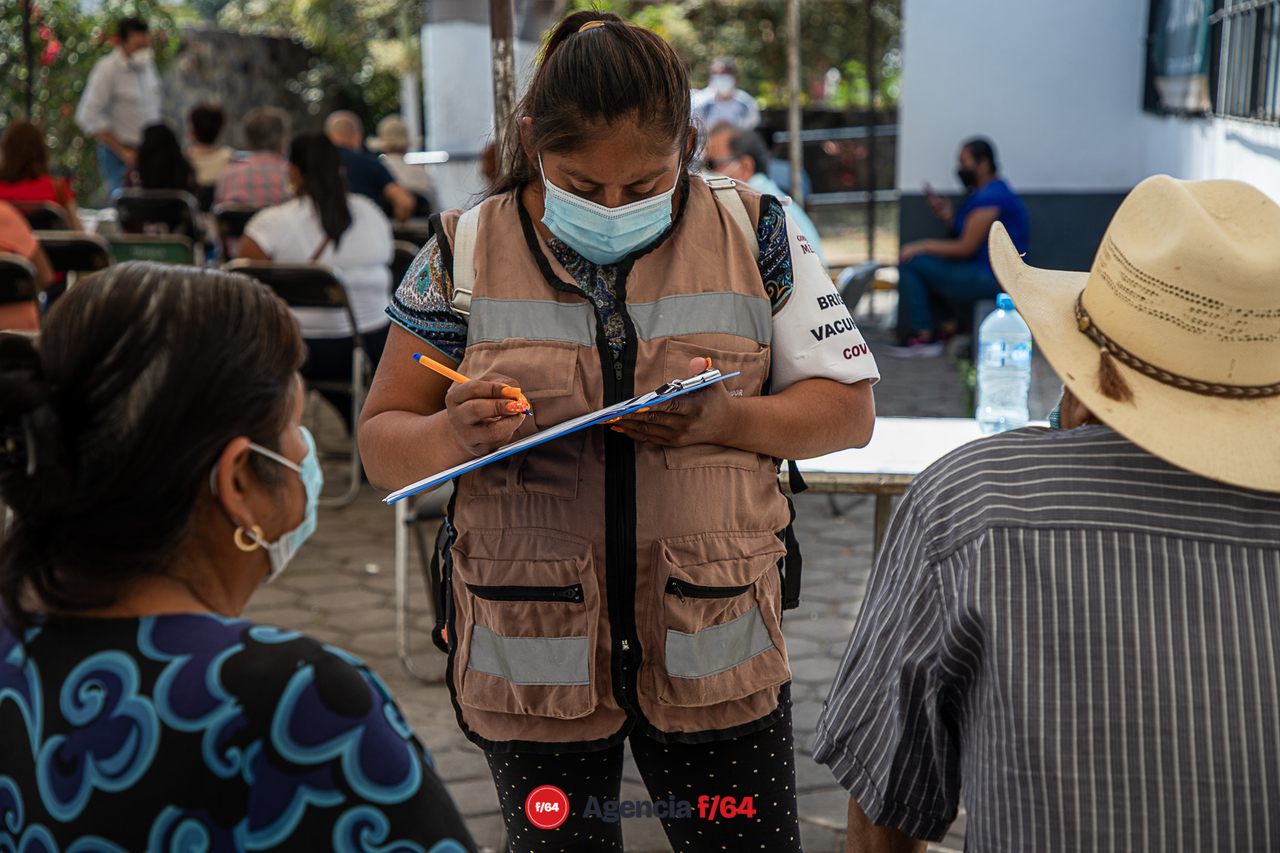 Adultos mayores recibiendo ayuda para llenar el formato de registro de vacunación contra COVID-19.