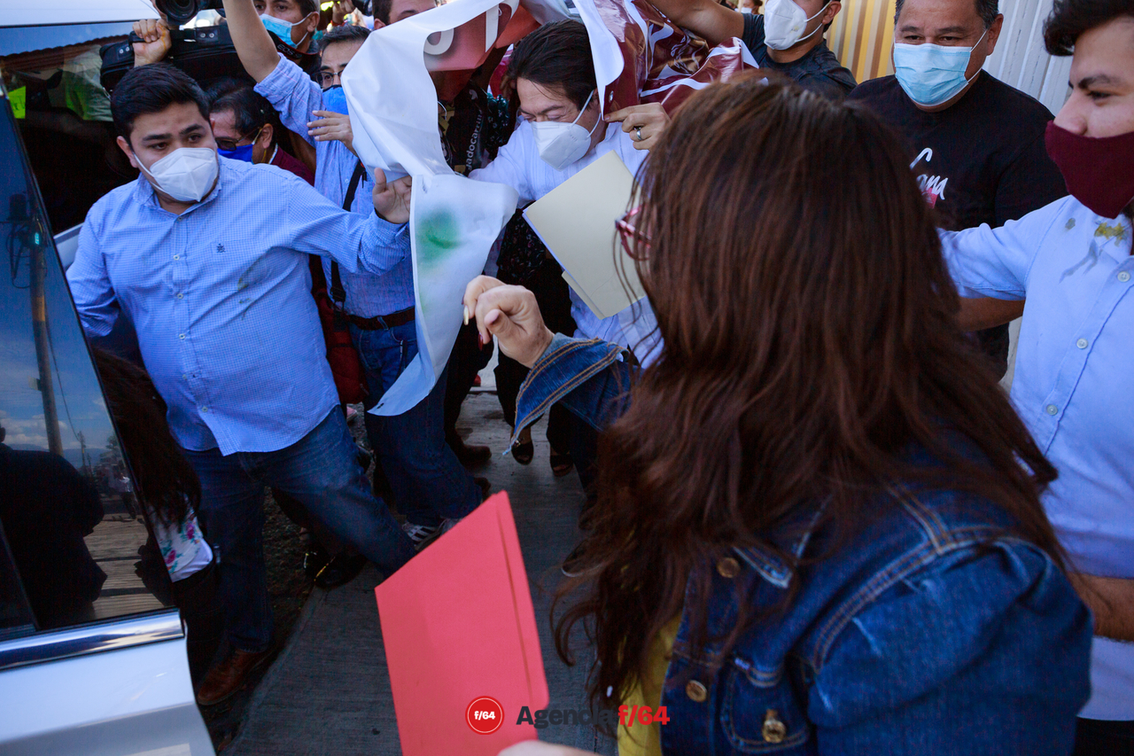 El presidente de Morena sale envuelto en lonas para protegerse de los manifestantes.